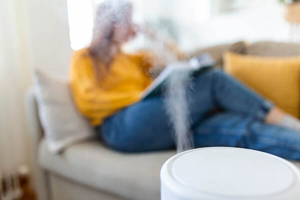 Air purifier in cozy white living room for filter and cleaning at home with woman reading a book